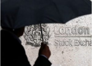A man shelters under an umbrella as he walks past the London Stock Exchange in London, Britain, August 24, 2015. REUTERS/Suzanne Plunkett/File Photo