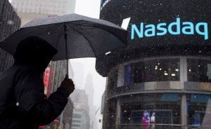 A man uses an umbrella to guard against snowfall as he walks past the Nasdaq MarketSite in Times Square, Midtown New York March 20, 2015. REUTERS/Adrees Latif